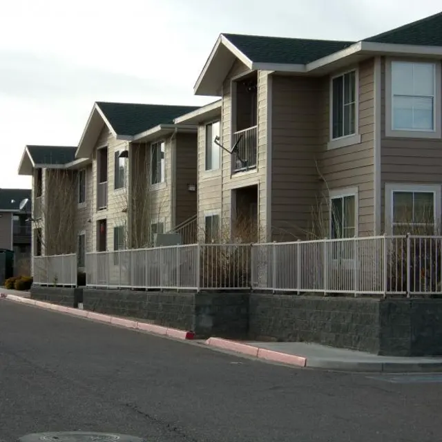 Apartment Buildings with Sidewalk Row of apartment buildings with balconies and a fence along the sidewalk.