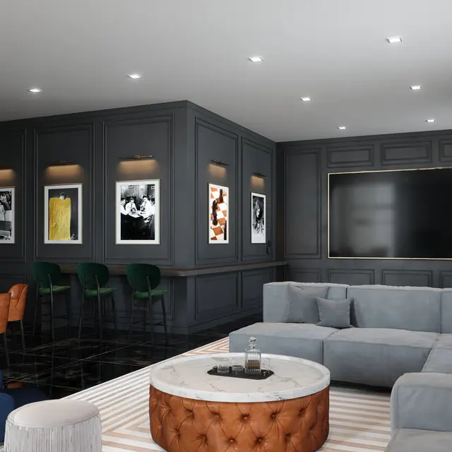 A stylish modern living room featuring dark walls, a large sectional sofa, coffee table, and a dining area with chairs. The room is well-lit with recessed lights and artwork on the walls.