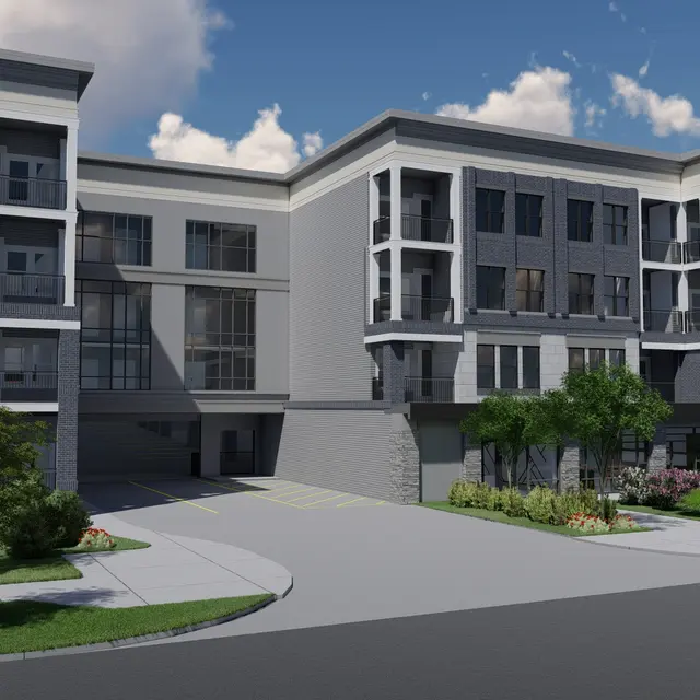 A modern apartment building with a sleek architectural design, featuring a combination of brick and siding, surrounded by landscaped greenery and blue skies with fluffy clouds.