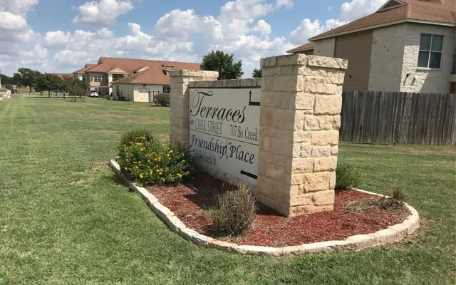 A stone sign marking the entrance to Terraces at 1085 Siesta Creek, with the words 'Friendship Place' beneath.