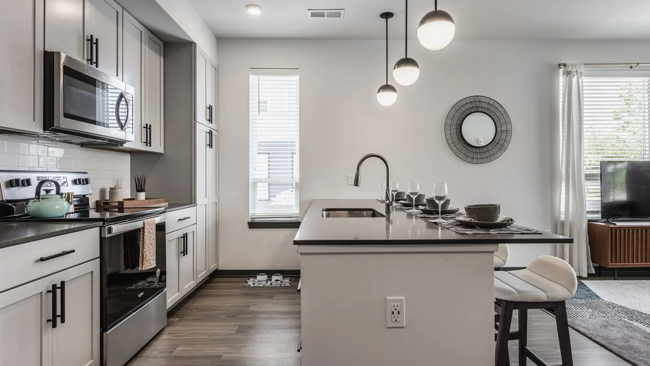 A modern kitchen featuring a sleek design with stainless steel appliances, a countertop with bar seating, and pendant lighting.