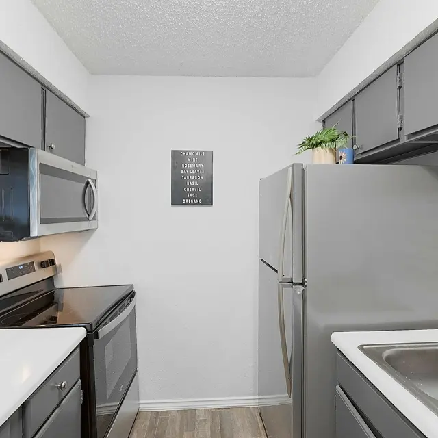 Modern kitchen featuring dark gray cabinets, stainless steel appliances, a white countertop, and a subway tile backsplash.