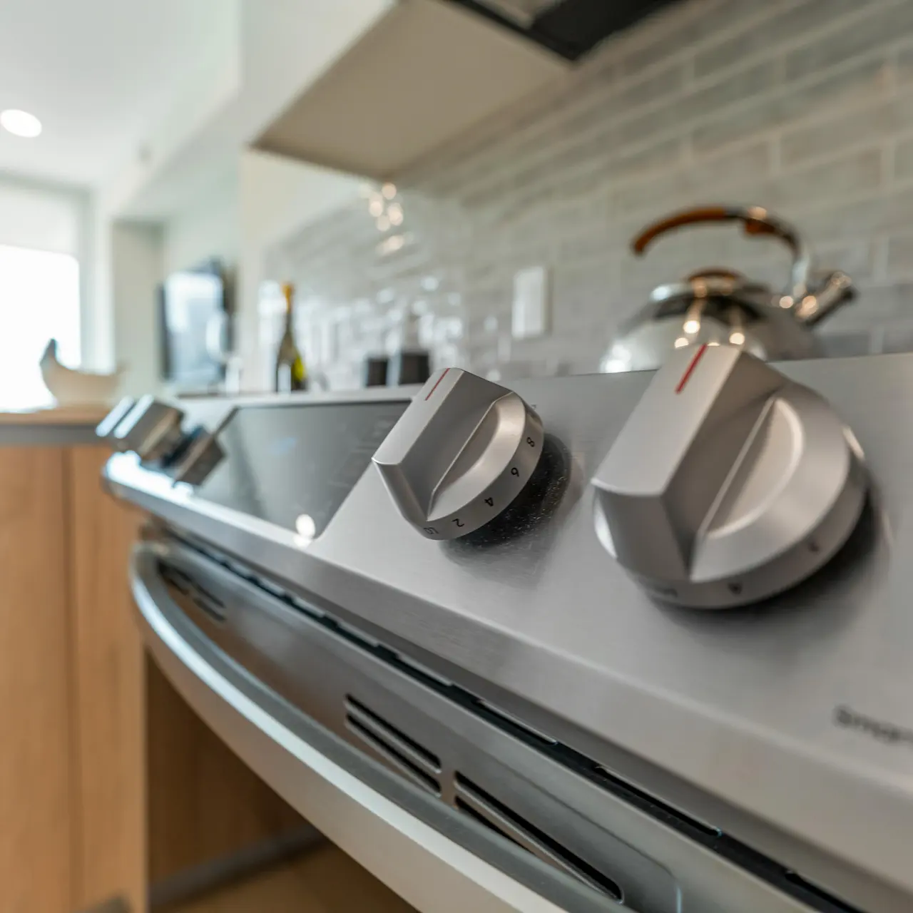 Close-up view of a modern stove top with sleek knobs and a contemporary kitchen background.