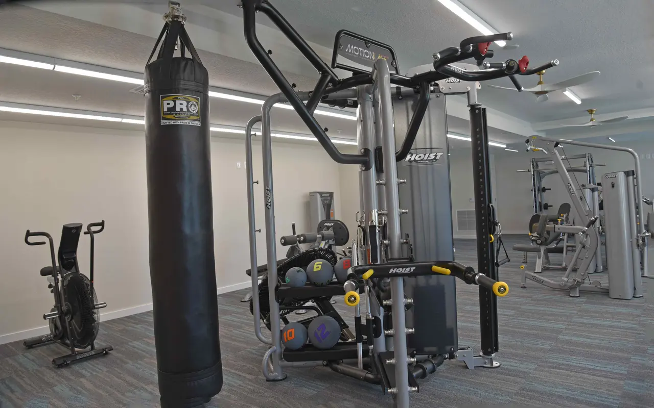 Interior of a gym featuring various workout equipment including a multi-station machine, a punching bag, and a stationary bike.