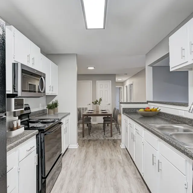 A modern kitchen featuring black appliances, white cabinetry, and a spacious layout.