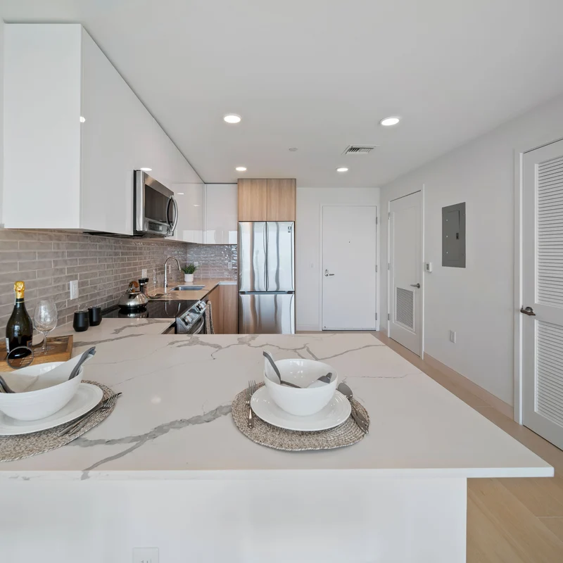 Modern Kitchen Interior A contemporary kitchen featuring a large island with two bowls, sleek cabinets, stainless steel appliances, and a light-colored backsplash.